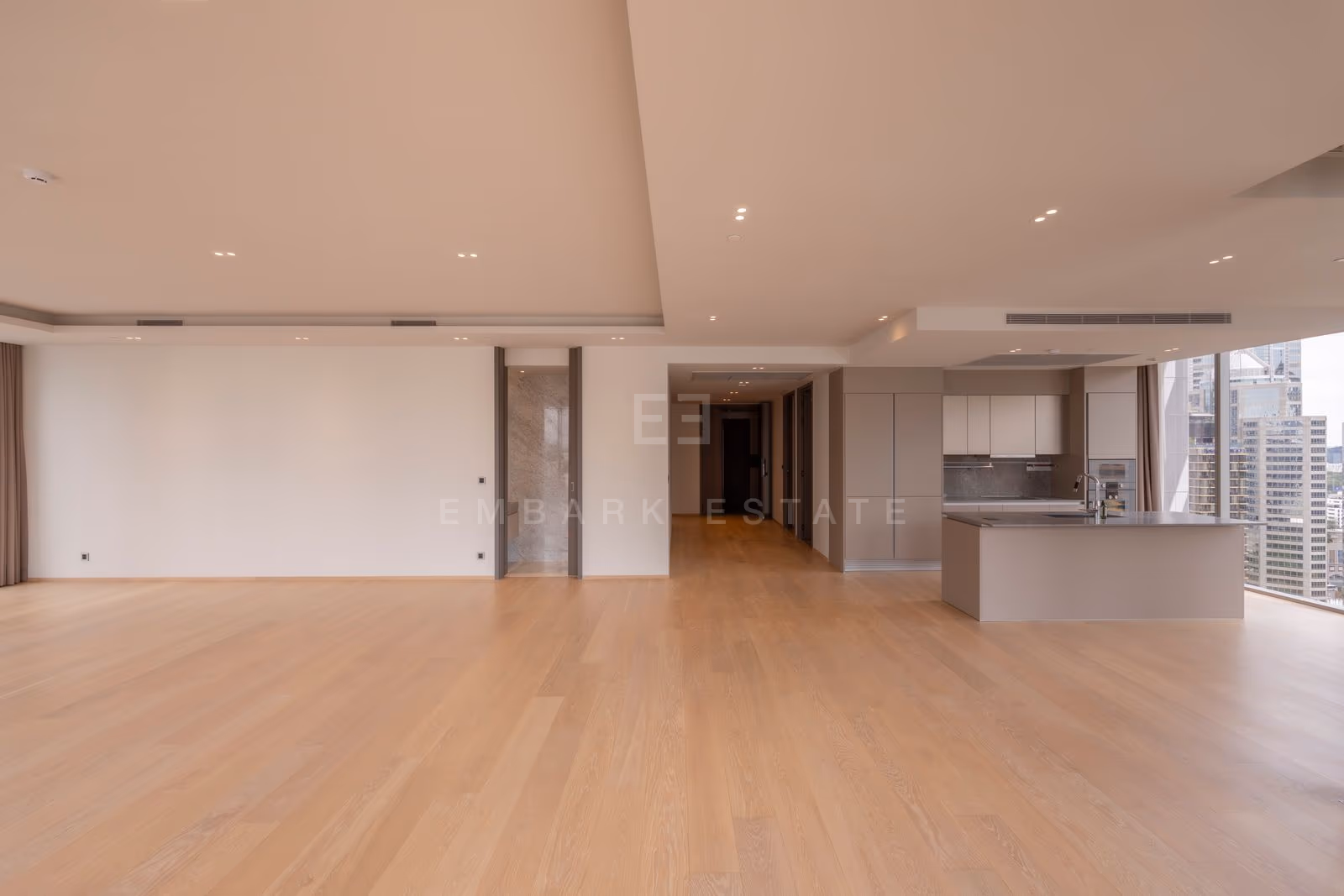 Looking from the living room towards the kitchen and the bedroom corridor in a three-bedroom residence at Tonson One Residence, pale oak floors throughout