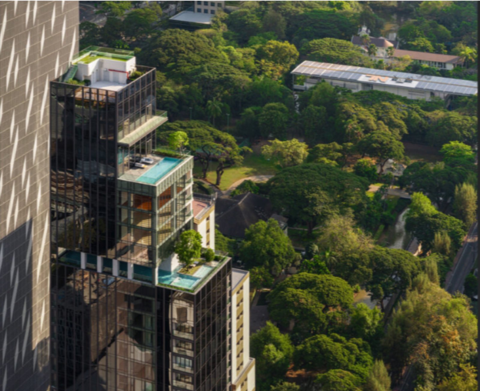 Aerial view of the cantilevered sky pools and gardens at Tonson One above the trees of Lumphini Park in central Bangkok