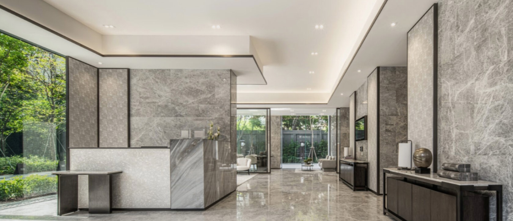 The grey-marble arrival lobby and concierge desk at Tonson One opening to a garden courtyard, central Bangkok