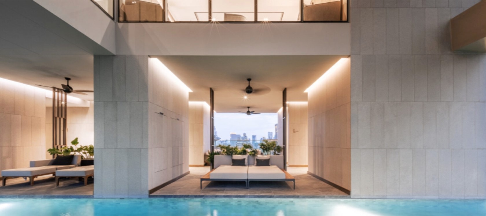 The indoor-outdoor swimming pool pavilion with daybeds and a city view at Tonson One, Bangkok