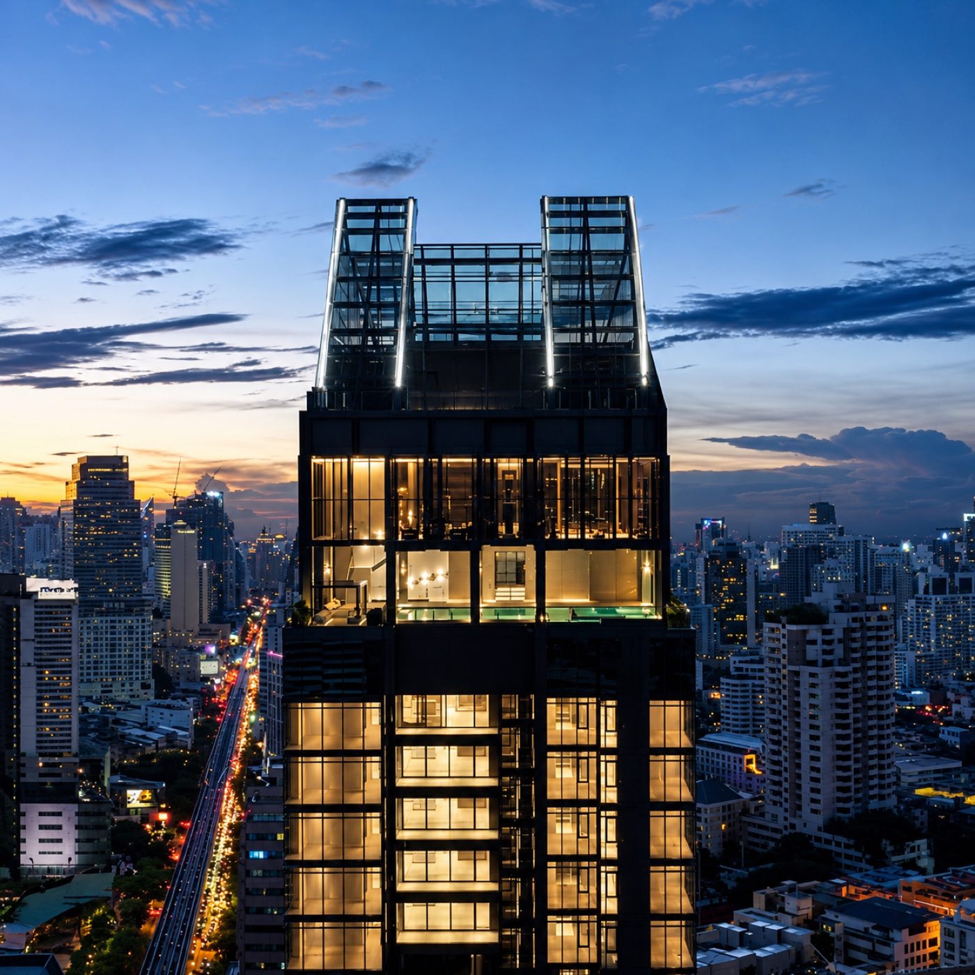 Vittorio Sukhumvit 39: the lit crown and sky lounge of the low-density tower above the Sukhumvit skyline at dusk in Bangkok