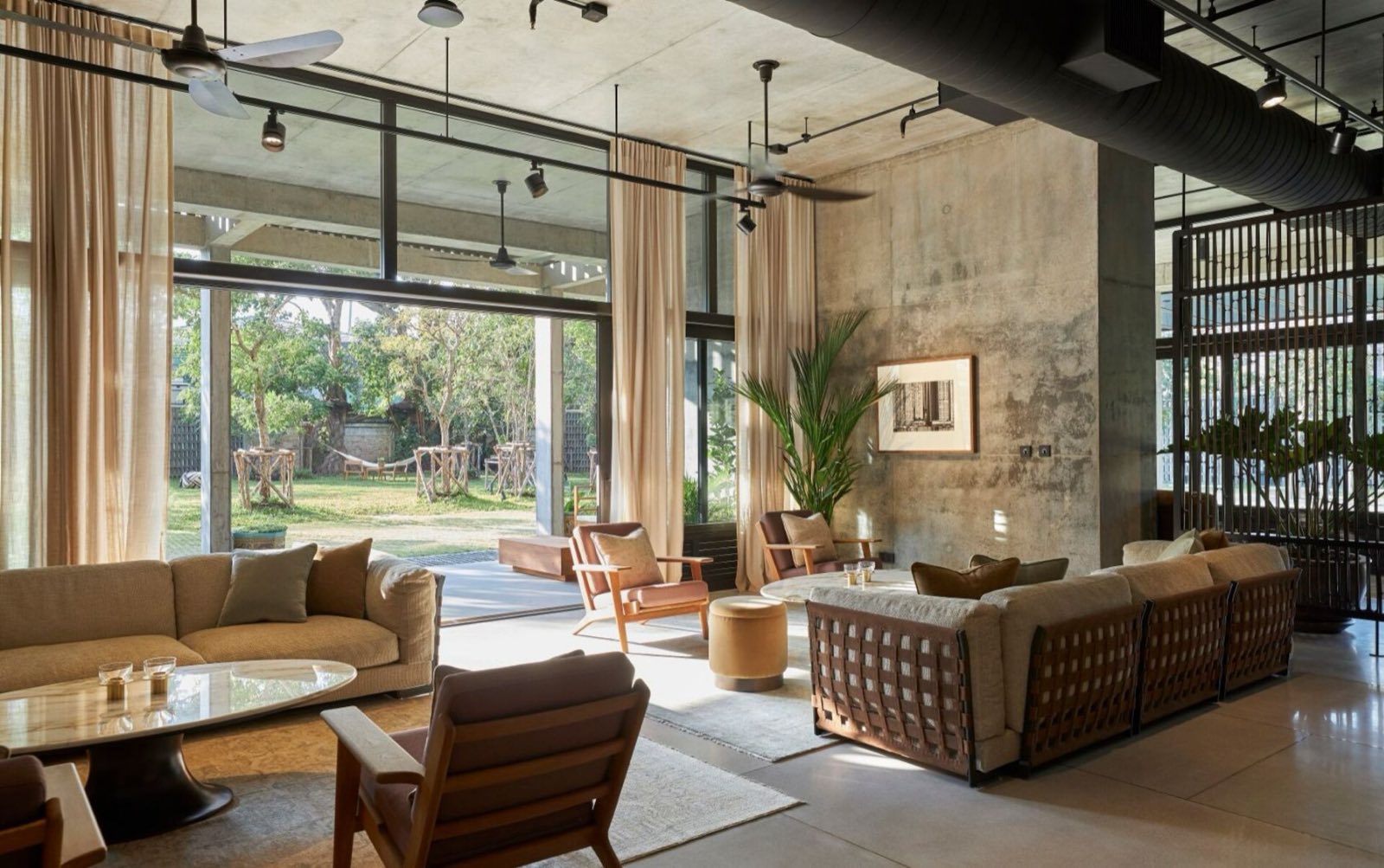 Windshell Naradhiwas lounge seating opening onto a private garden, exposed concrete walls