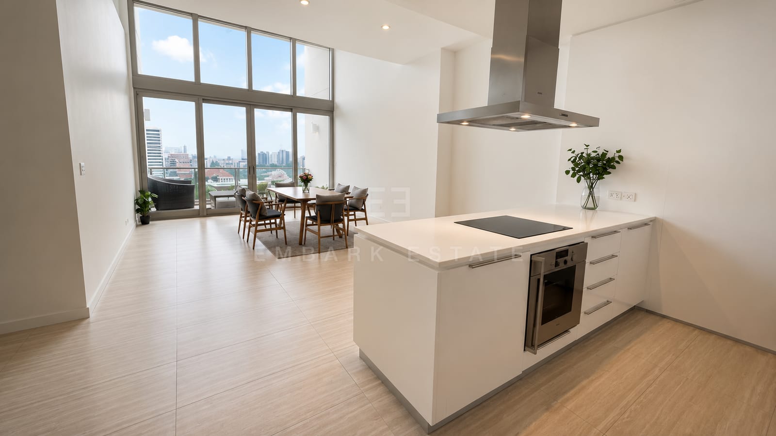 The double-height living and dining room at 185 Rajadamri, the dining table beneath tall glazing with the kitchen island alongside