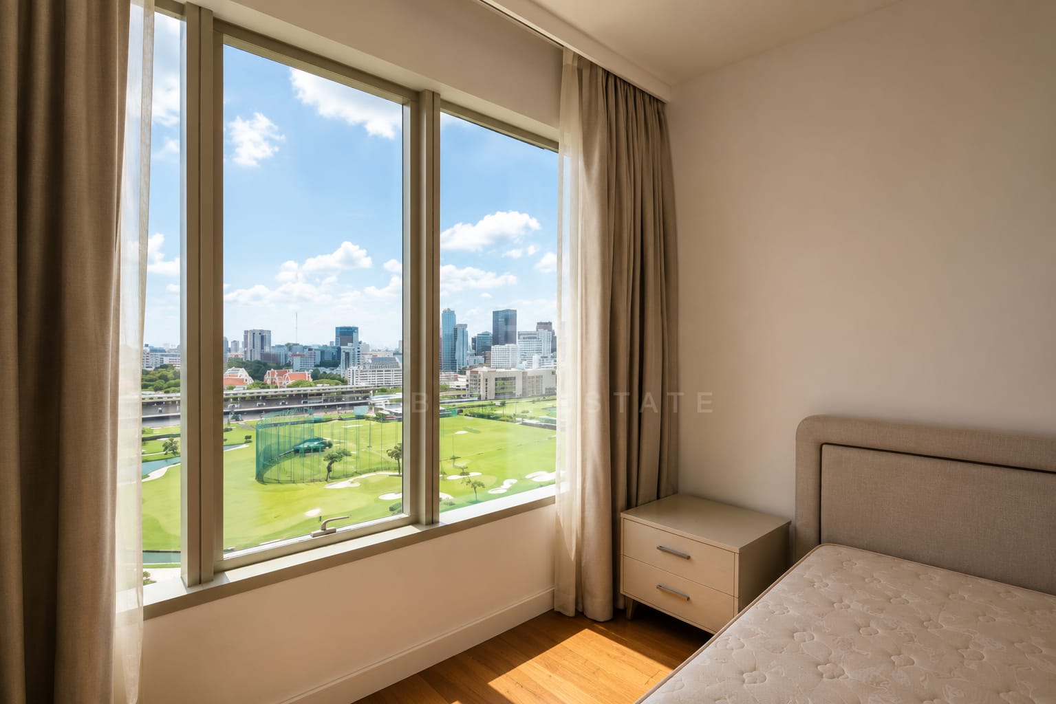 A bedroom at 185 Rajadamri, corner glazing over the Royal Bangkok Sports Club opposite