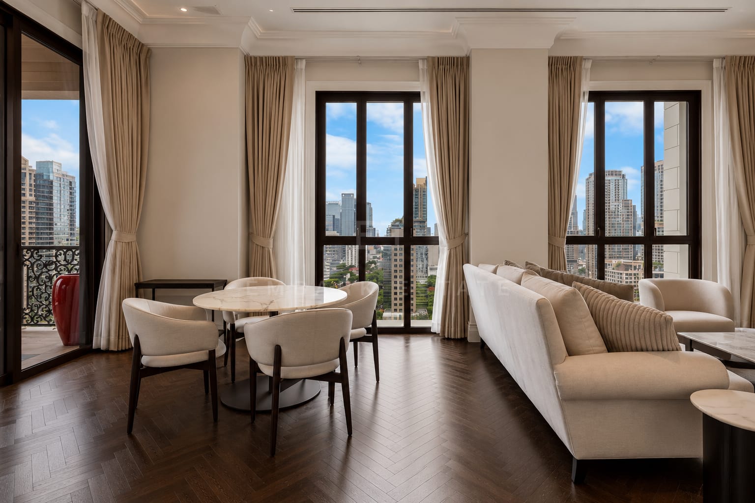 The living and dining room of the 120 square metre residence at 98 Wireless, a round marble table and long sofa on herringbone parquet with French windows onto the balcony
