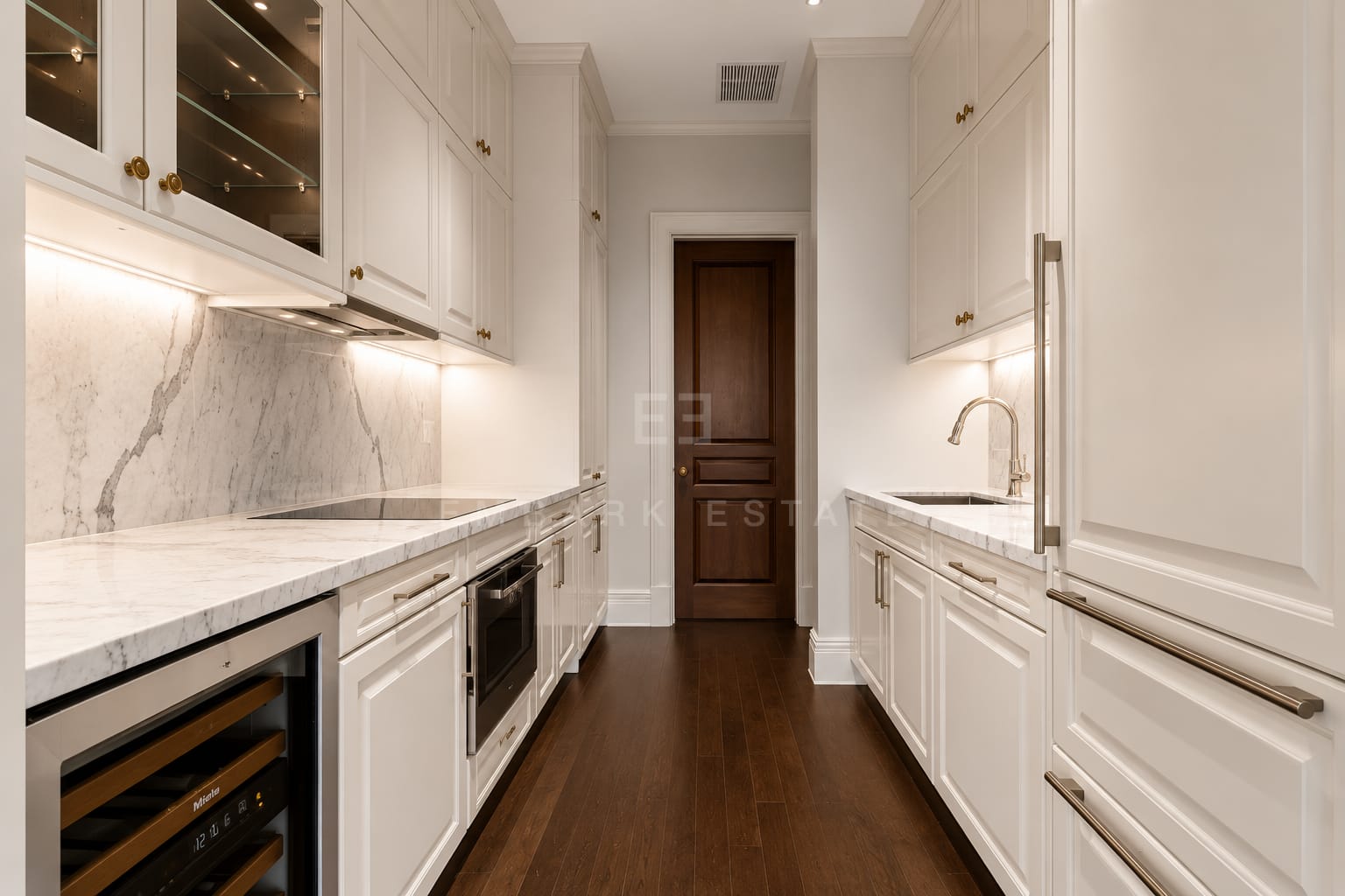 The kitchen at 98 Wireless, panelled cabinetry with brass handles under a marble worktop and splashback