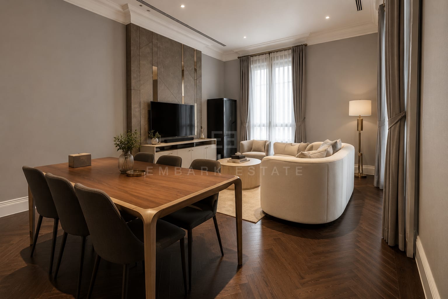 The dining table at 98 Wireless, walnut with six charcoal chairs on herringbone parquet beside the curved sofa