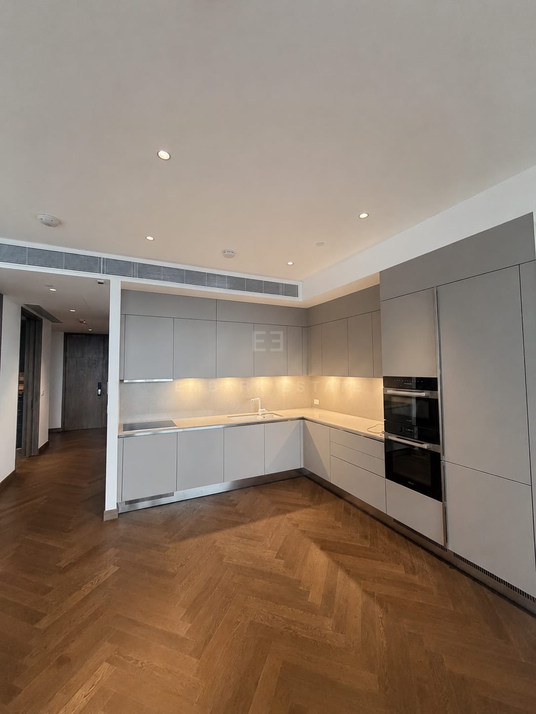 Kitchen at Dusit Residences, Dusit Central Park, Bangkok, with integrated ovens and herringbone oak flooring