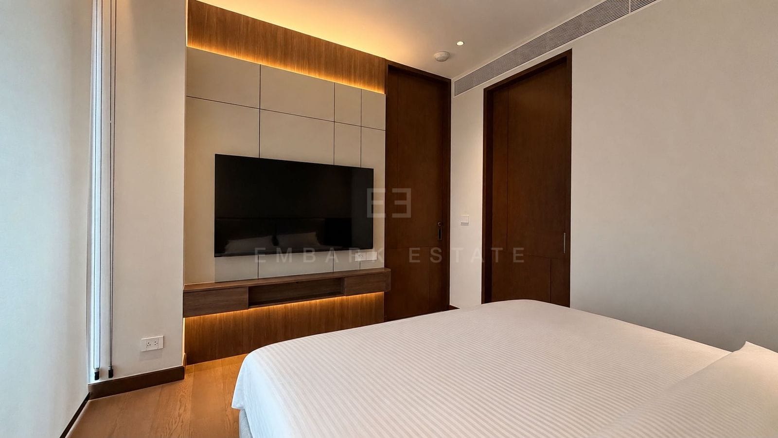 The bedroom at Dusit Parkside, Dusit Central Park, the television on a panelled wall above a timber shelf with cove lighting