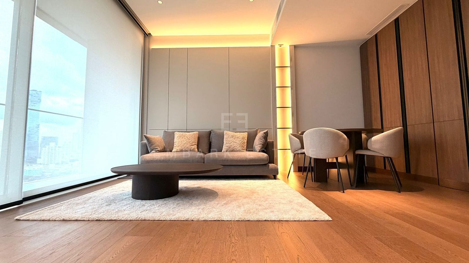 The living room at Dusit Parkside, Dusit Central Park, the sofa on a rug with the dining table beyond and glazing to one side