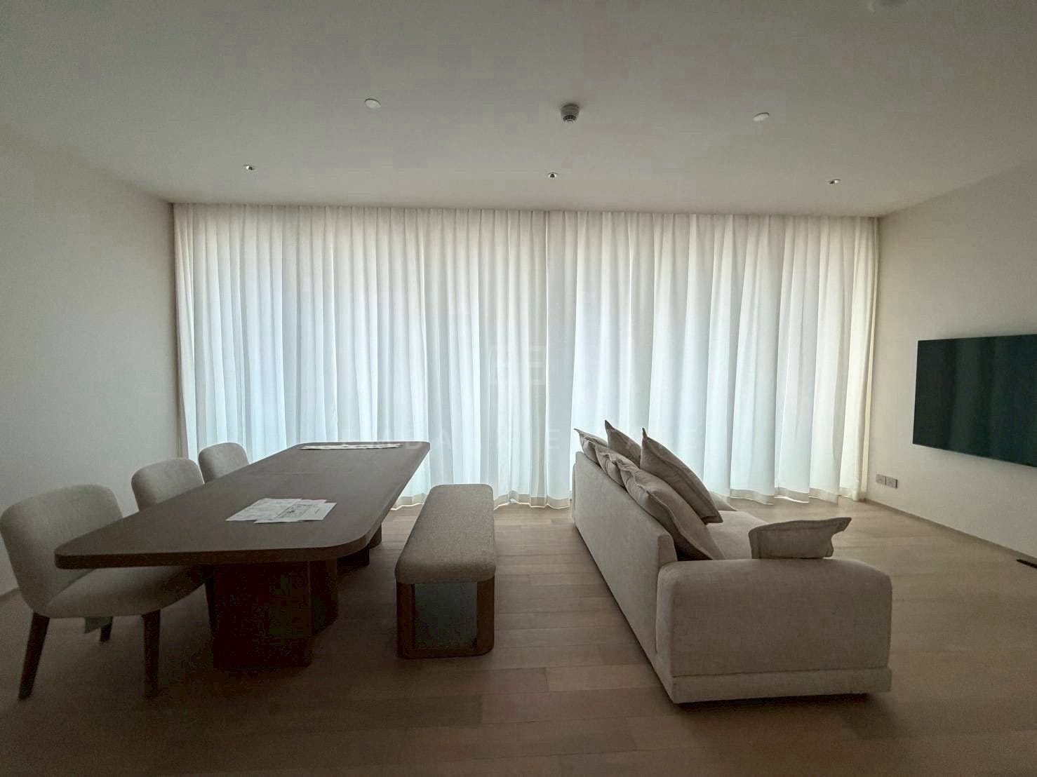 The living and dining room at EI8HTEEN SEVEN, the oak table and bench with a cream sectional under sheer curtains