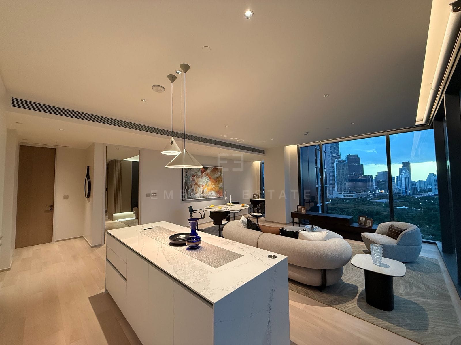 Kitchen island at EI8HTEEN SEVEN, Bangkok, looking through the open living room to Lumphini Park through floor-to-ceiling glass