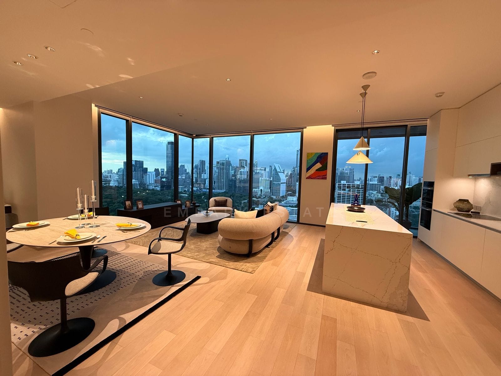 The open living, dining and kitchen at EI8HTEEN SEVEN, Bangkok, wrapped in corner glazing over Lumphini Park and the skyline
