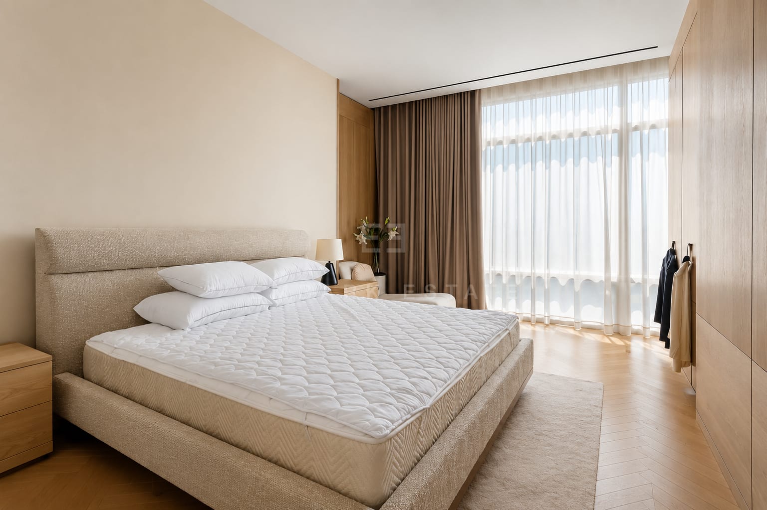 A bedroom at Four Seasons Private Residences, an upholstered headboard between bedside tables with an oak wardrobe alongside