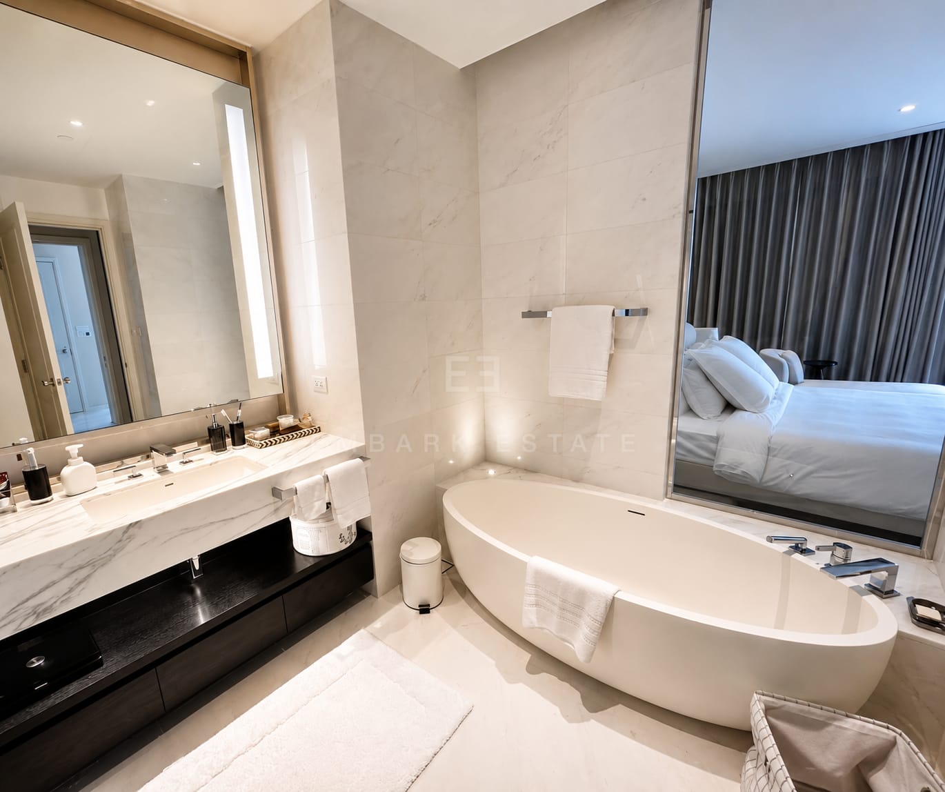 The bathroom at Four Seasons Private Residences, twin basins on marble above a dark timber unit with an oval freestanding tub