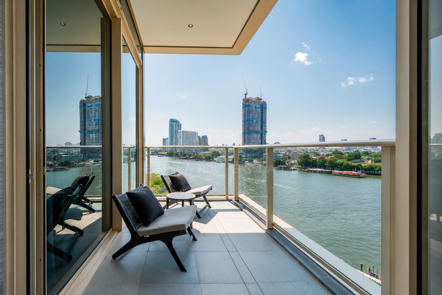 The balcony at Four Seasons Private Residences, two lounge chairs behind a glass balustrade above the river
