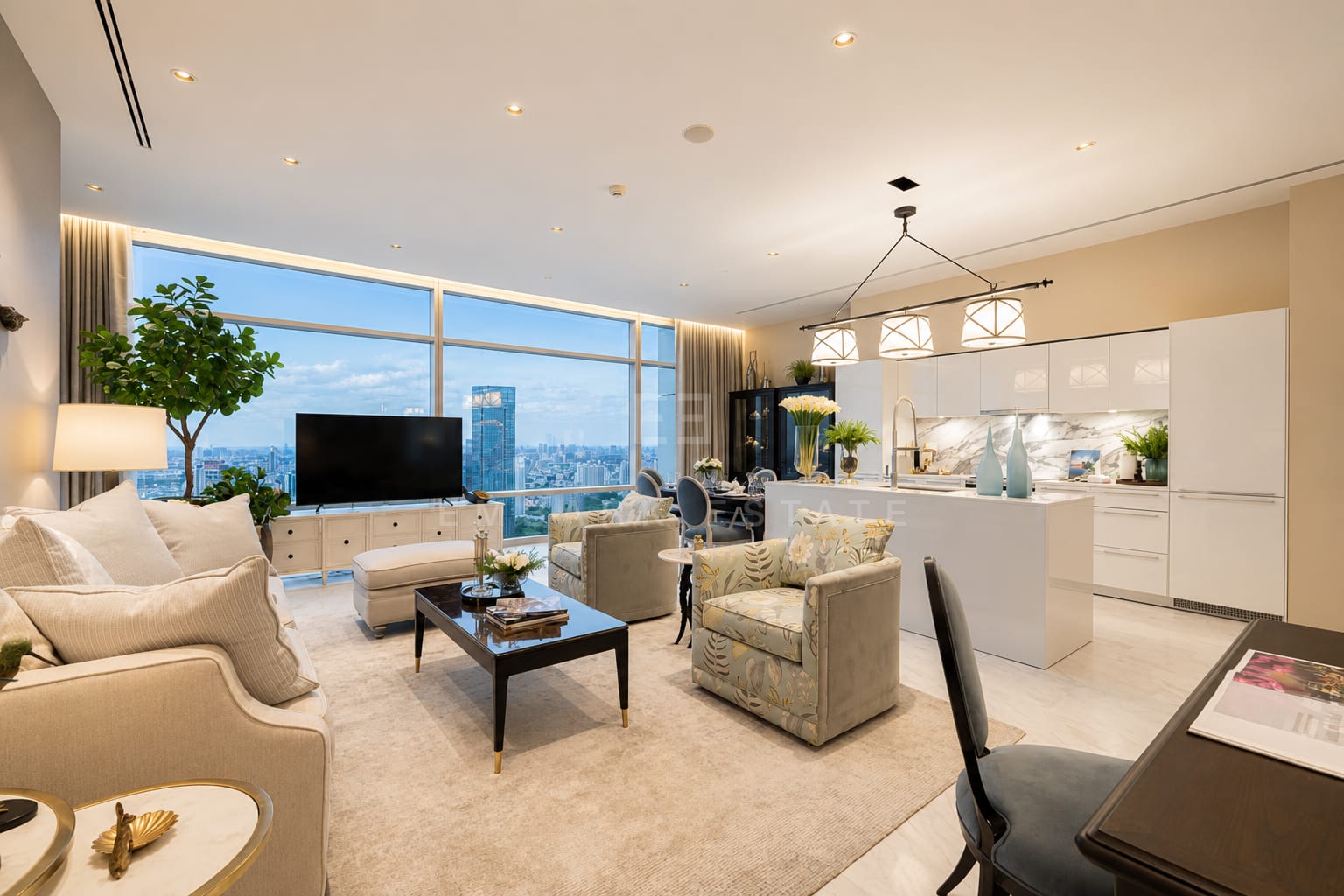 The living room of the 140 square metre residence at Four Seasons Private Residences, upholstered armchairs and a dark timber table with the marble kitchen island beyond