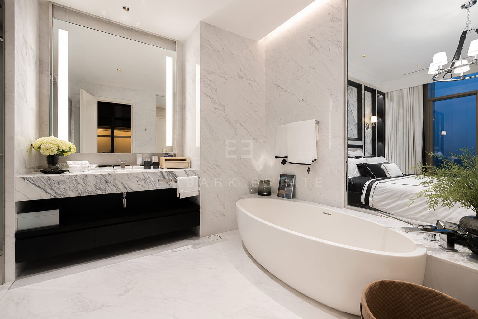 The main bathroom at Four Seasons Private Residences, a marble vanity on a dark timber unit with an oval freestanding tub and the bedroom beyond the mirrored partition