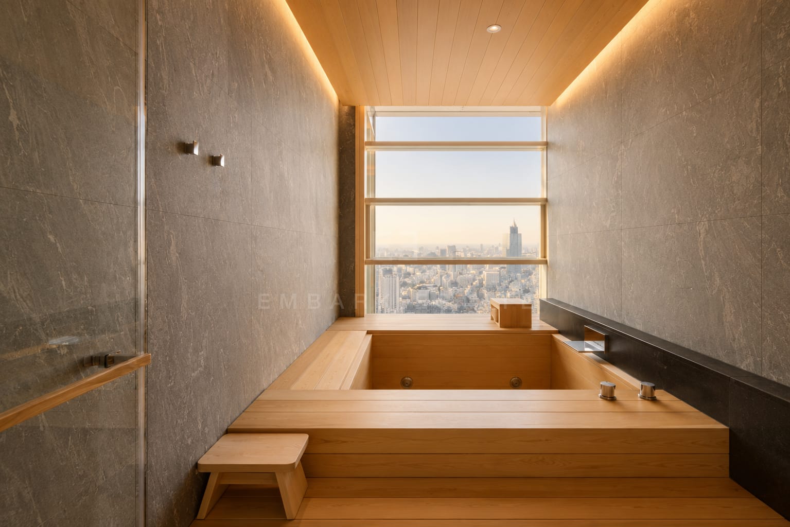 The bathroom at Four Seasons Private Residences, a timber soaking tub set into a stone platform beneath a slot window over the city