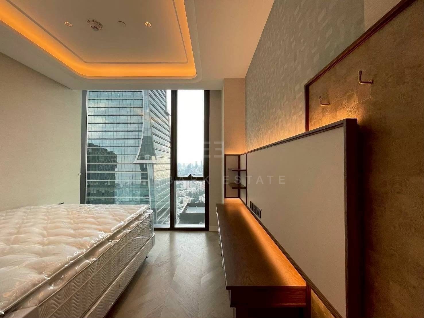 A bedroom at ONE89 Wireless from the side, a long timber console beneath an upholstered panel with the tower opposite through the glass