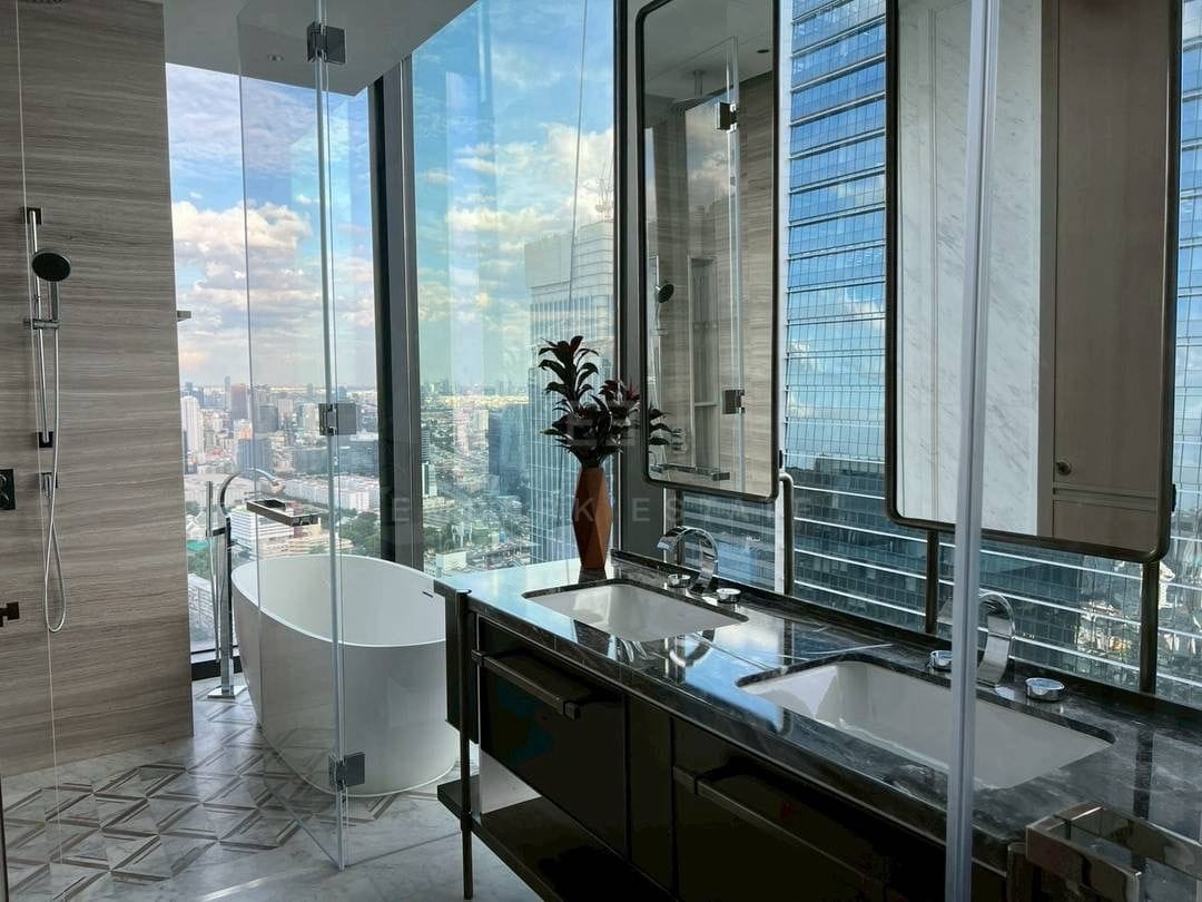 The main bathroom at ONE89 Wireless, a freestanding tub against full-height glazing over the city with twin basins on a dark stone vanity and a glazed shower