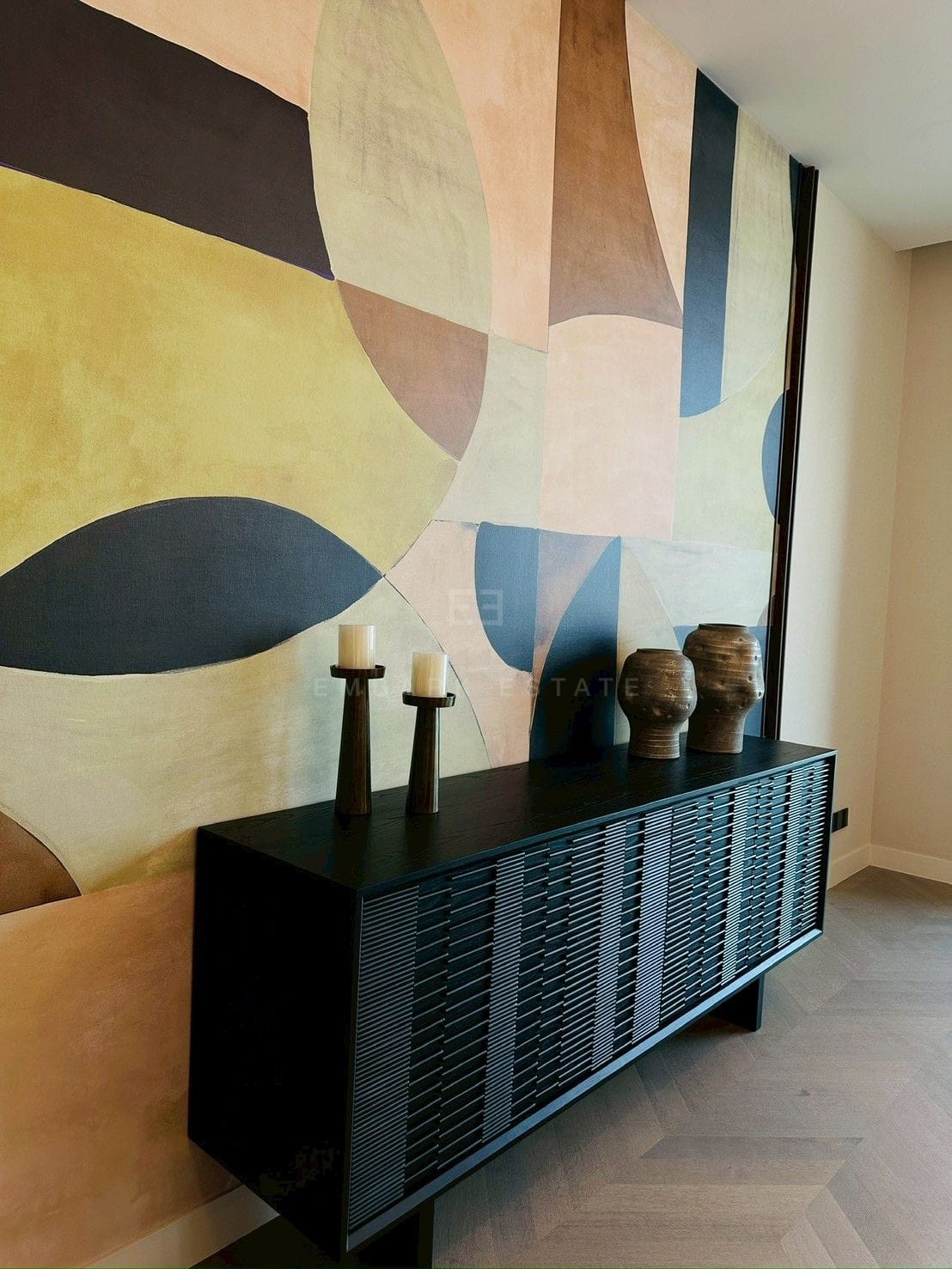 Entrance hall at ONE89 Wireless, Bangkok, with a full-height abstract panel wall above a ribbed black console on herringbone oak