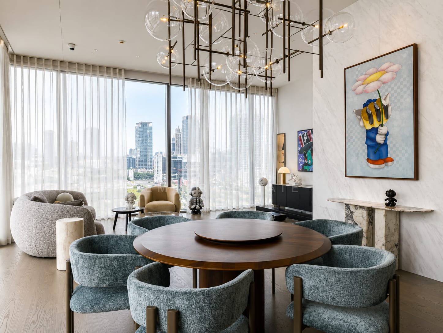 The dining room of the 157 square metre residence at Scope Langsuan, a round walnut table with six teal chenille chairs under a bubble glass chandelier