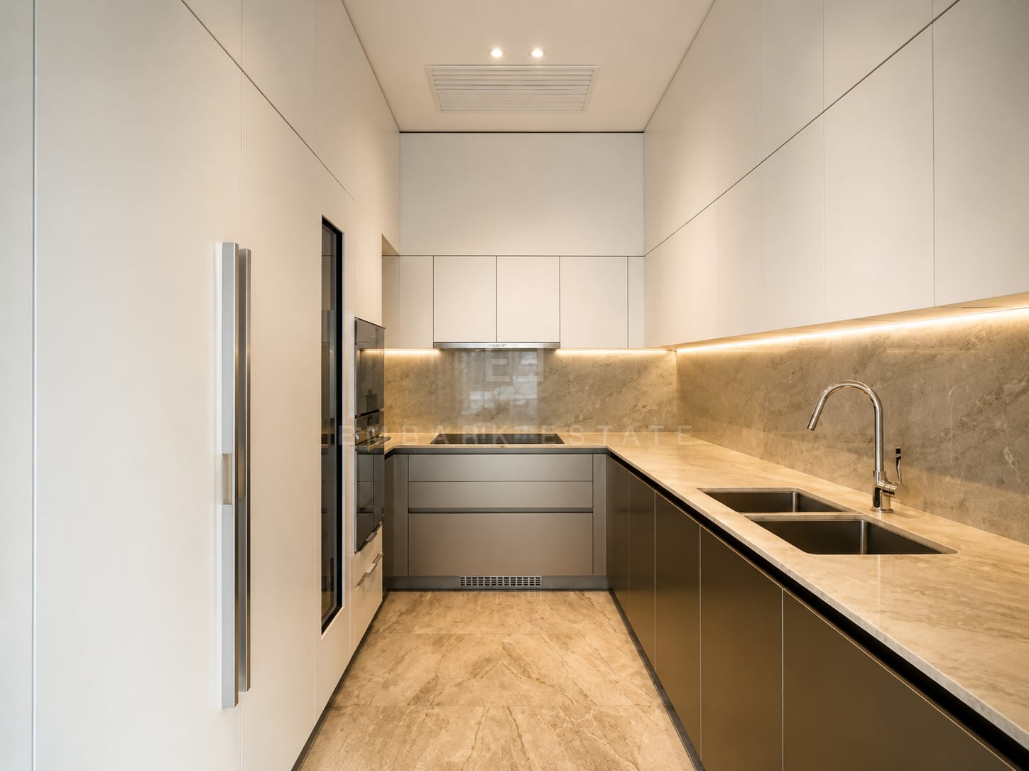 The kitchen at Scope Langsuan, bronze base units under a stone worktop and splashback with lighting beneath the upper cabinets