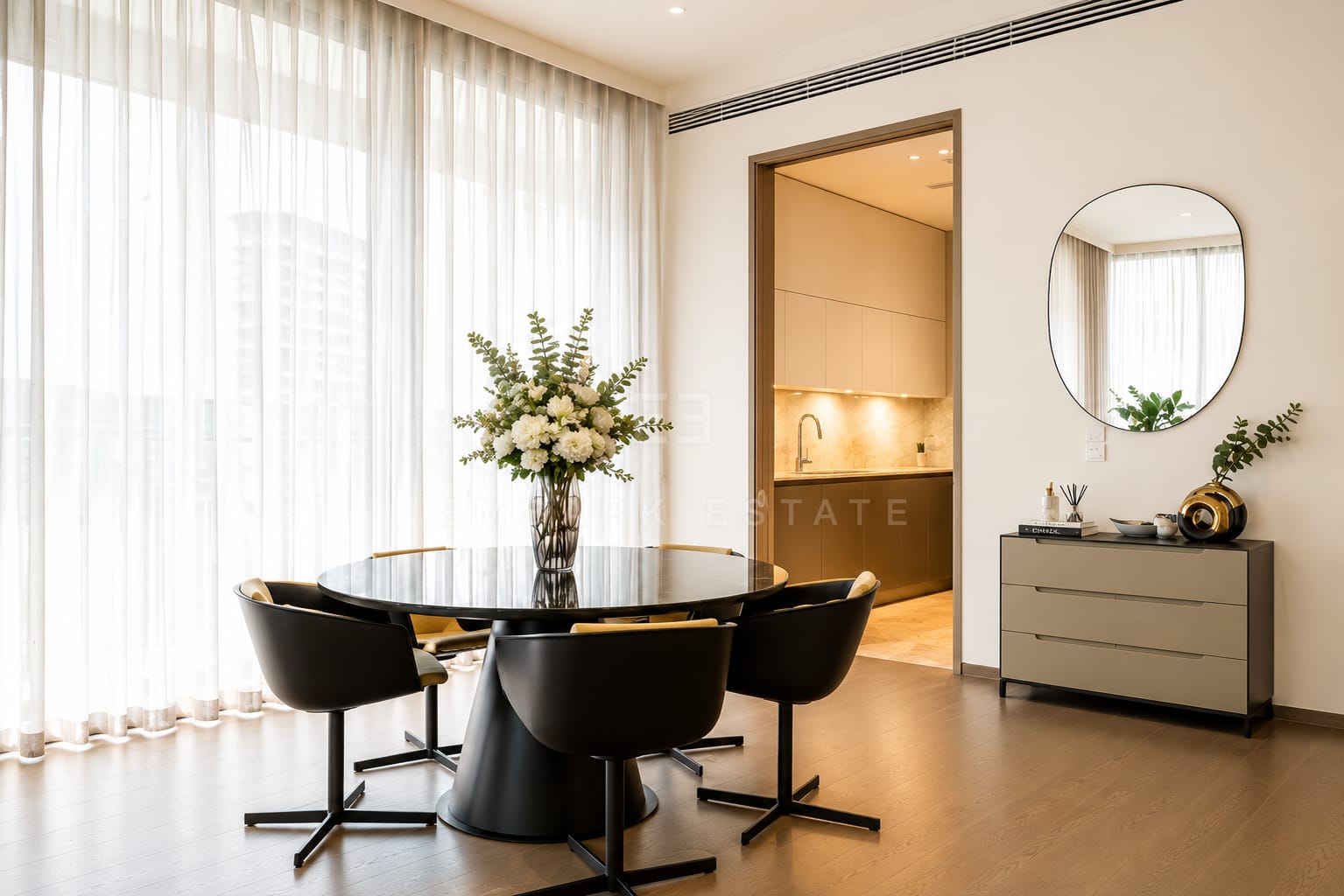 The dining table at Scope Langsuan, a round black top with four swivel chairs and the pantry lit through the doorway
