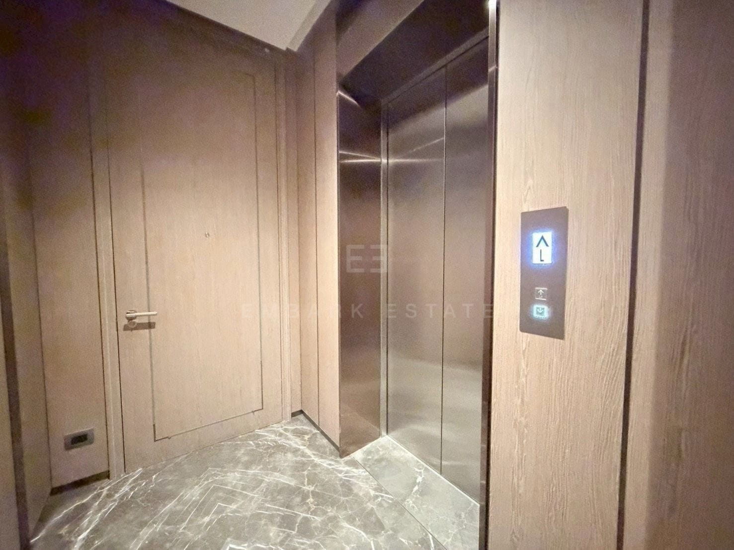 Private lift lobby at Scope Langsuan, Bangkok, panelled in pale oak with a marble floor