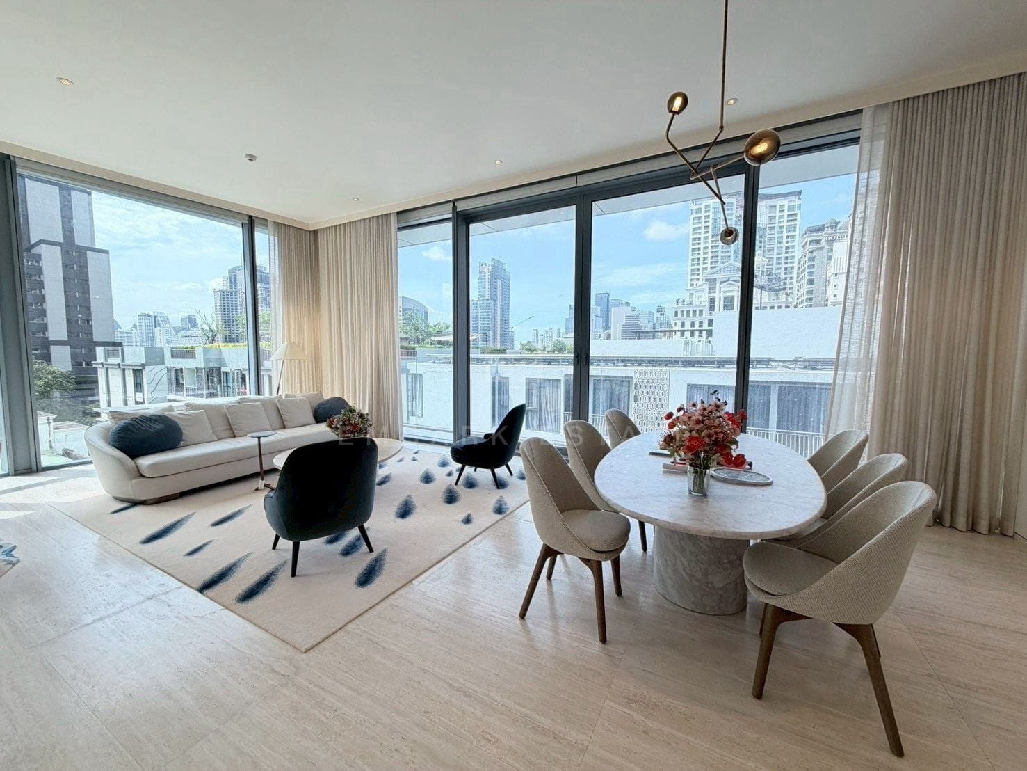 The living and dining rooms at Scope Langsuan, Bangkok, wrapped in floor-to-ceiling glass over the Langsuan rooftops