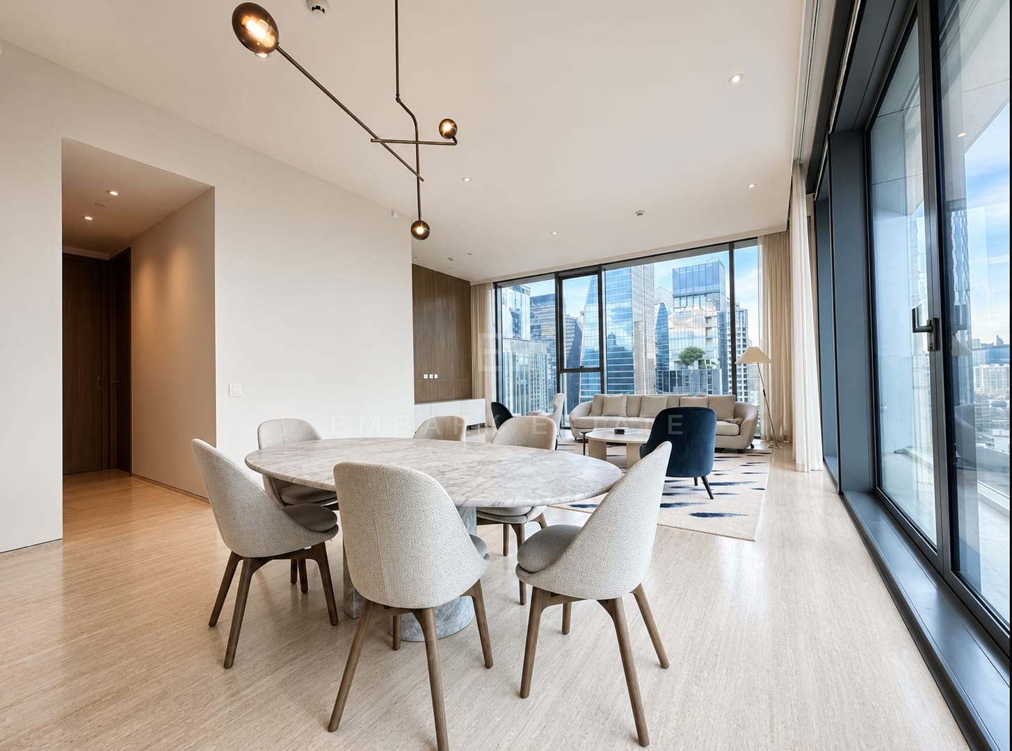 The dining table at Scope Langsuan, an oval travertine top with six chairs under a brass pendant