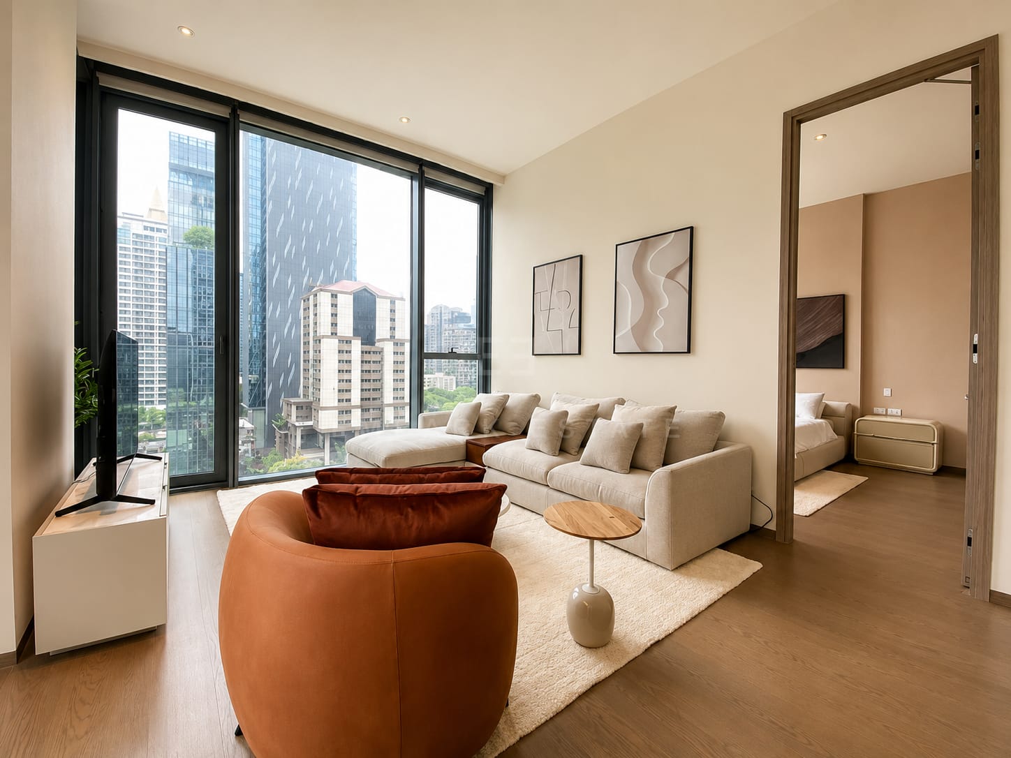 The living room of the 85 square metre residence at Scope Langsuan, a modular sofa and tan leather armchair with the bedroom through the open door