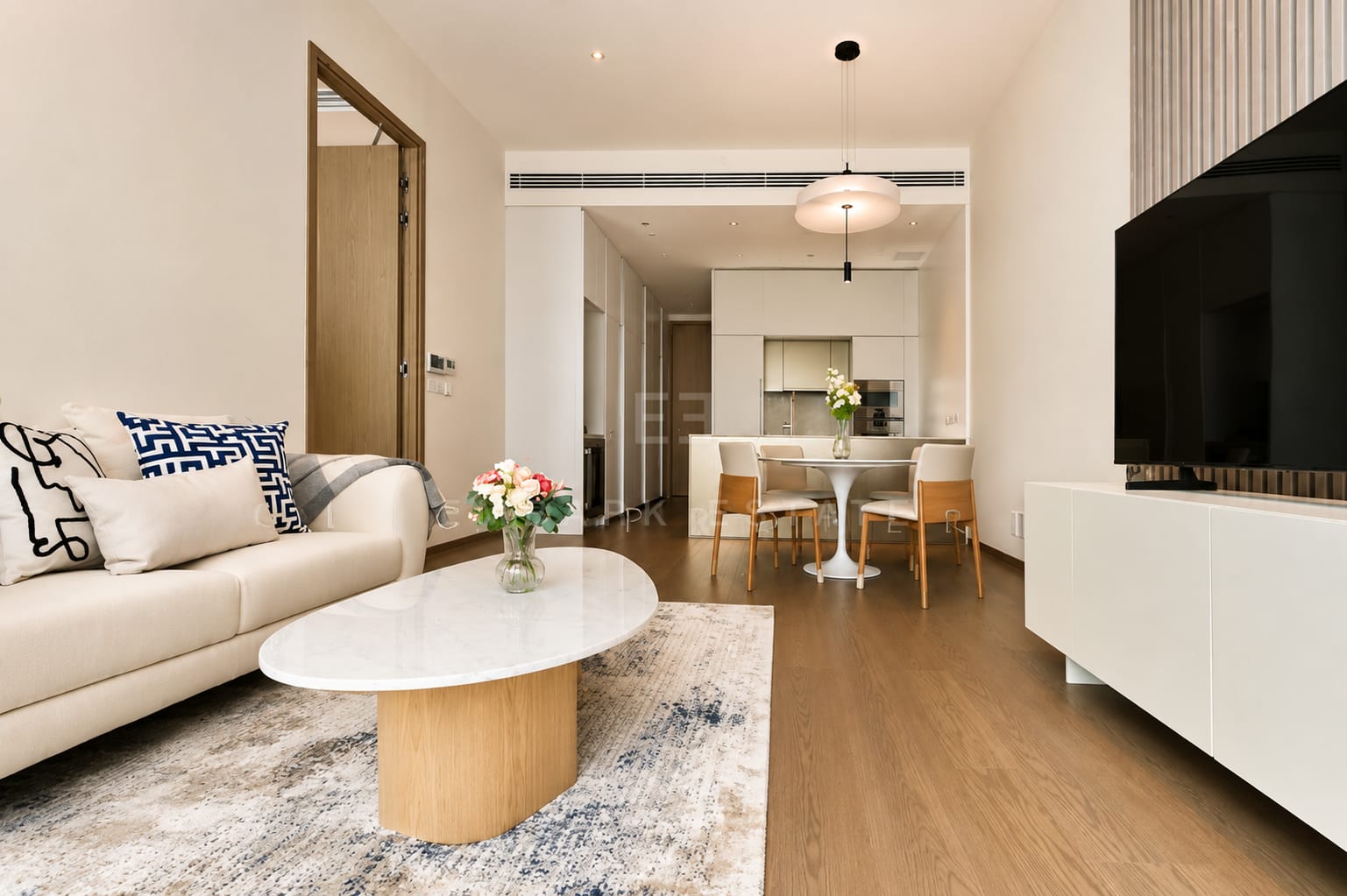 The living room of the 85 square metre residence at Scope Langsuan, a marble table on a timber base with a fluted timber wall behind the television