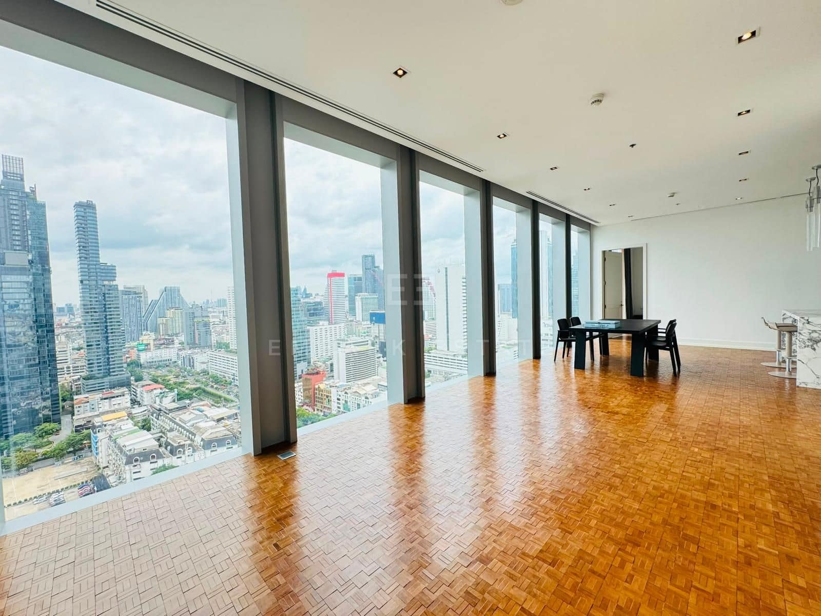 The living room of a two-bedroom residence at The Ritz-Carlton Residences Bangkok on the 25th floor, parquet floors running to a wall of glass over the city