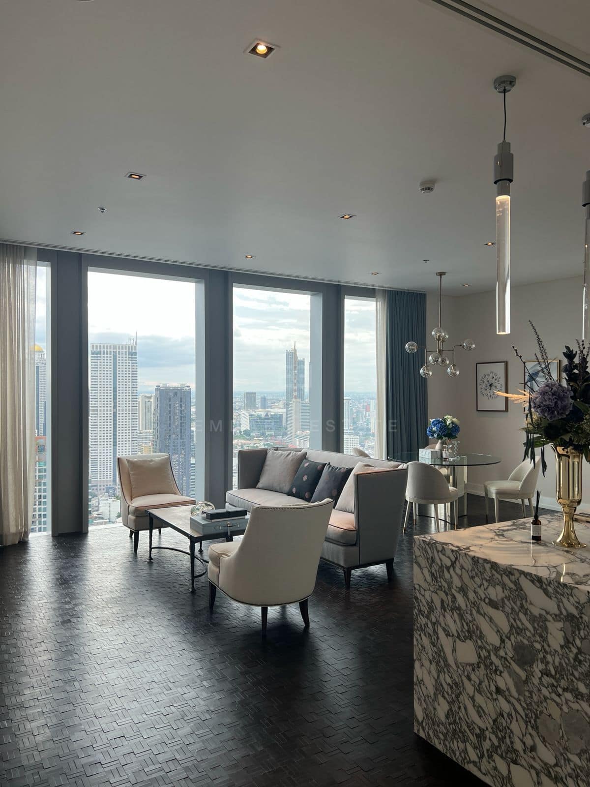 The living room at The Ritz-Carlton Residences Bangkok on the 43rd floor, furnished, with the city through full-height glass