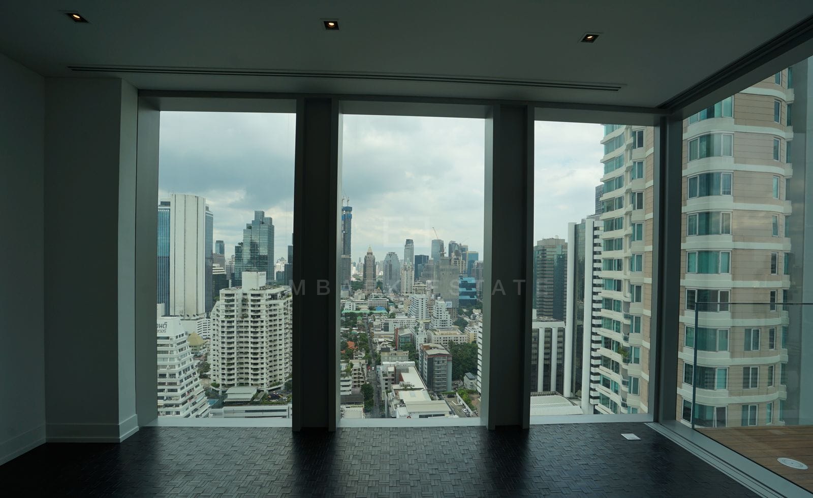 The living room at The Ritz-Carlton Residences Bangkok, columns of floor-to-ceiling glass over the Sathorn skyline