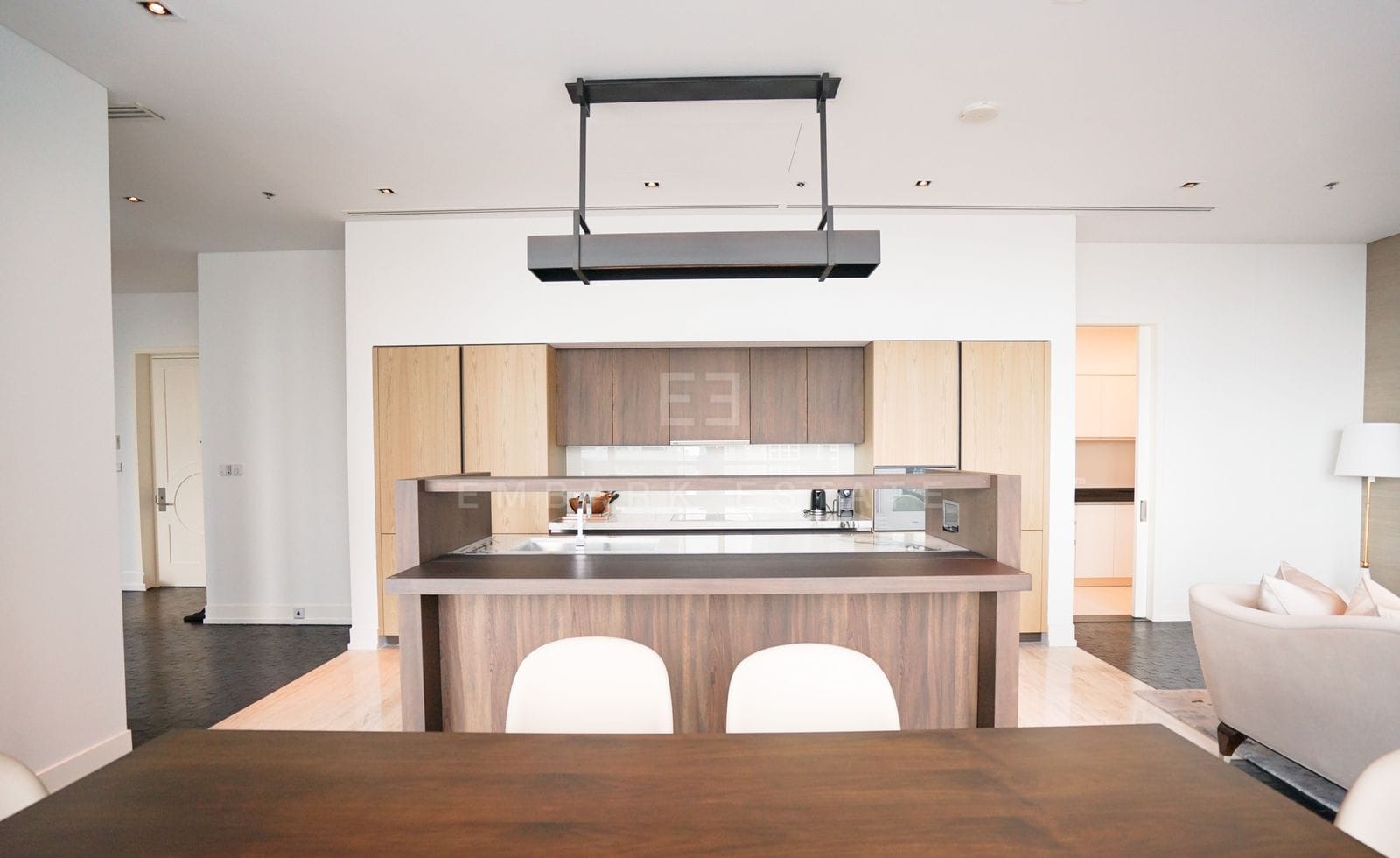 The kitchen of the residence seen from the dining table, a dark oak island with raised shelf under pale oak cabinetry