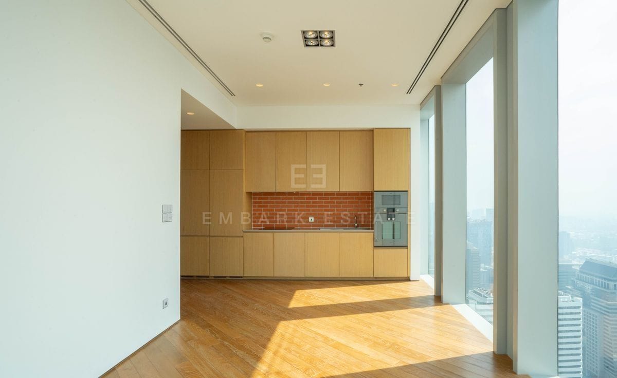 The kitchen of the duplex, an oak cabinetry wall with a brick-red tiled splashback and integrated ovens