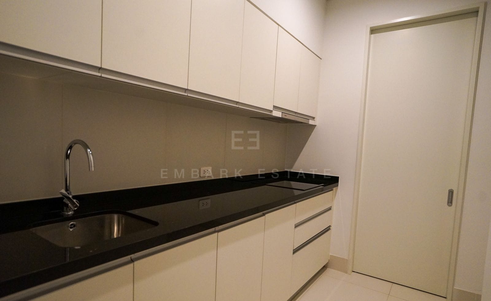 The utility kitchen of the 228 sq.m residence at The Ritz-Carlton Residences Bangkok, cream cabinetry and a black stone counter