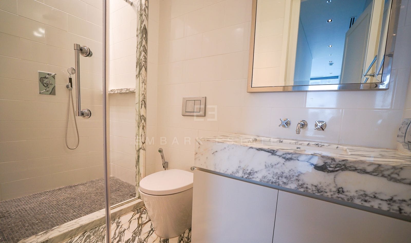 The same bathroom in warmer light, the marble vanity ledge in the foreground
