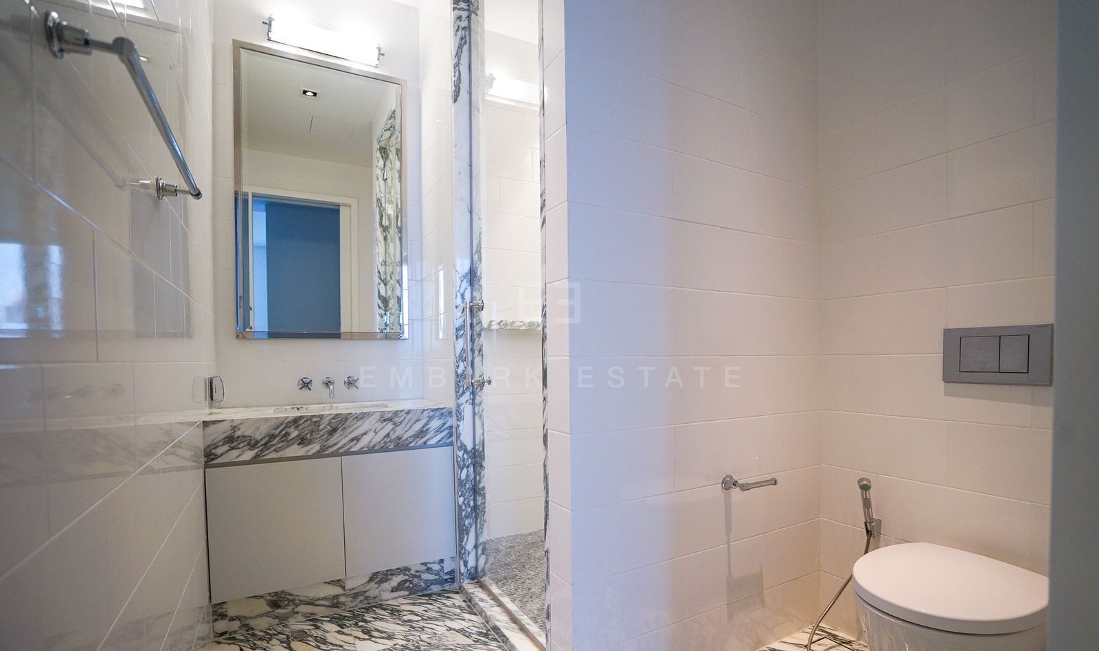 The same bathroom from its doorway, marble columns framing the WC