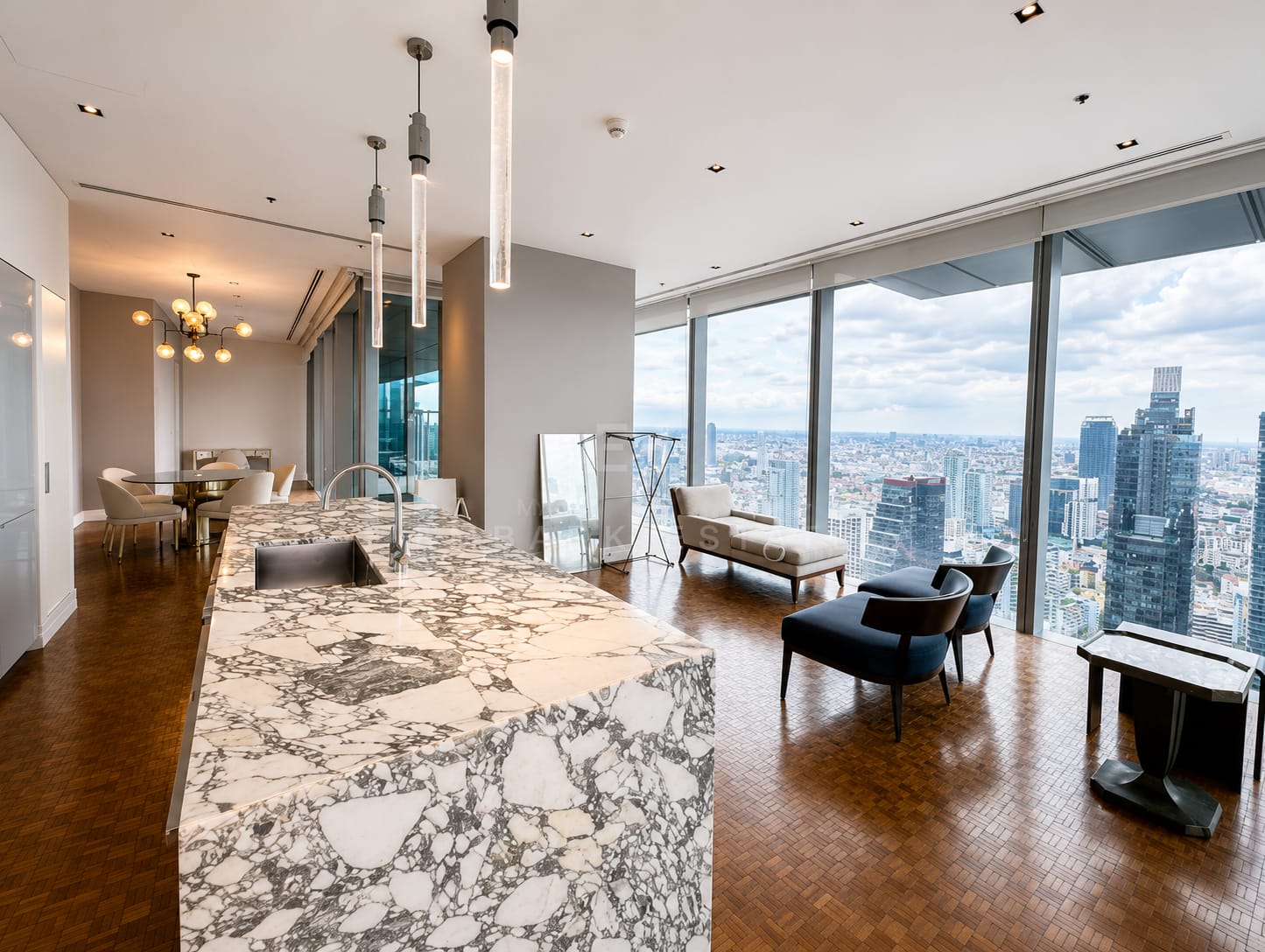 The living and dining room of the 248 square metre residence at The Ritz-Carlton Residences Bangkok, the marble island in the foreground and the terrace glazing along the far wall
