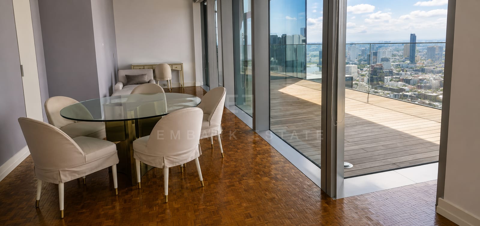 The dining table at The Ritz-Carlton Residences Bangkok, a round glass top on a brass base with sliding glass onto the timber terrace