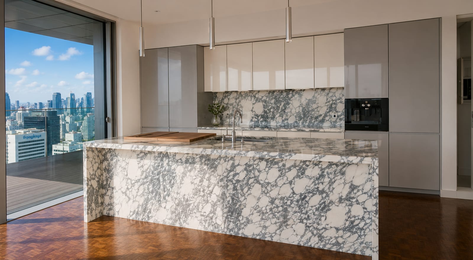 The kitchen at The Ritz-Carlton Residences Bangkok, an Arabescato marble island against grey cabinetry with the terrace through the glass