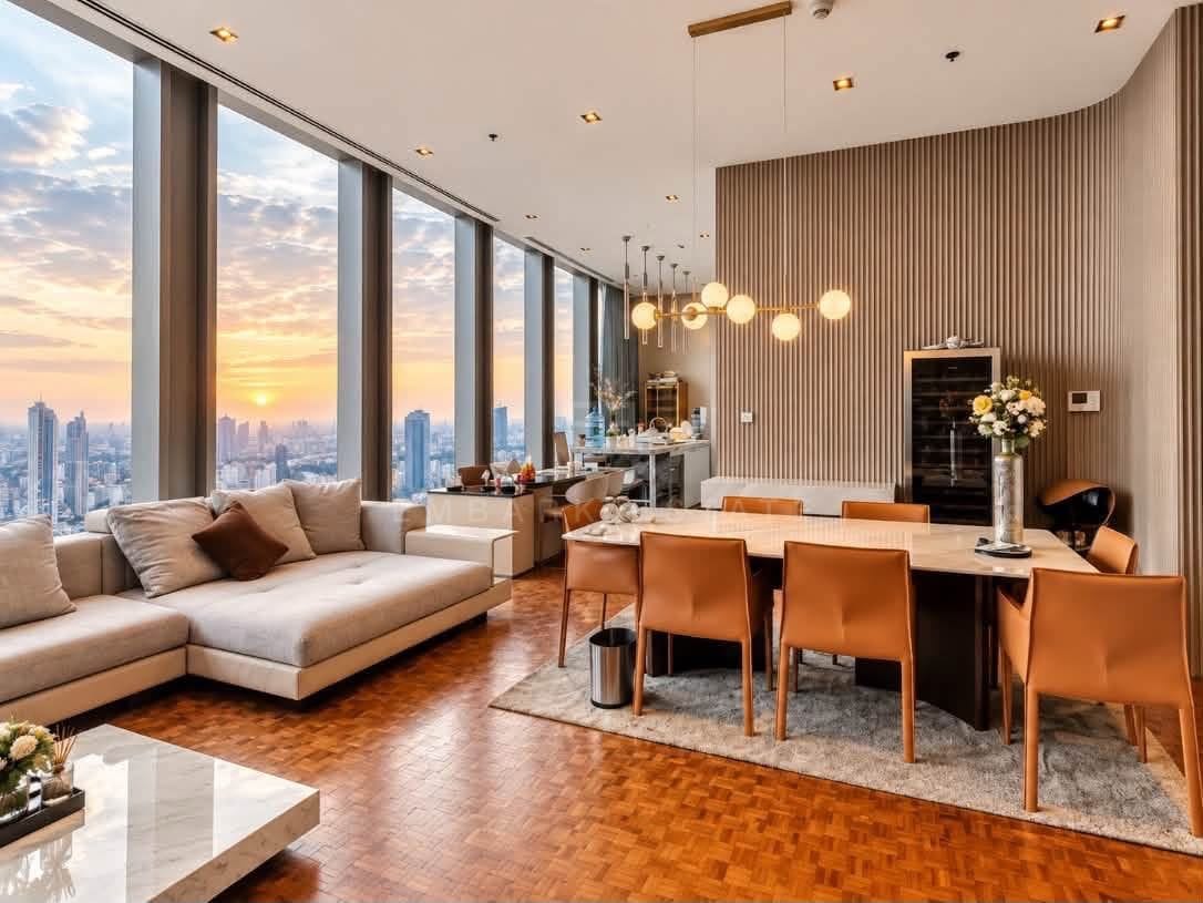 The living room of the 276 square metre residence on the 68th floor of The Ritz-Carlton Residences Bangkok at sunset, a cream sectional sofa and leather dining chairs on parquet beside full-height glazing over the city