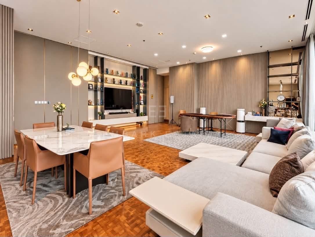 The living room at The Ritz-Carlton Residences Bangkok, a marble dining table with tan leather chairs, the sectional sofa and a television wall with built-in shelving