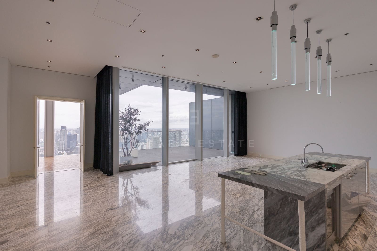 The kitchen island at The Ritz-Carlton Residences Bangkok on level 63, veined stone against full-height glass onto central Bangkok