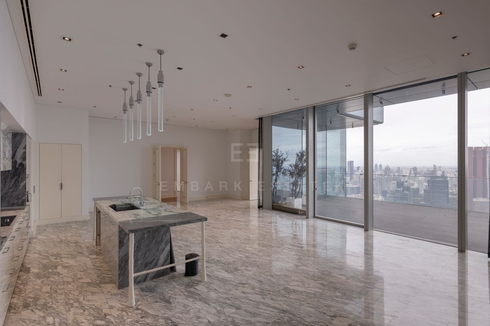 The kitchen and terrace doors at The Ritz-Carlton Residences Bangkok, the island looking out to the corner terrace and the skyline