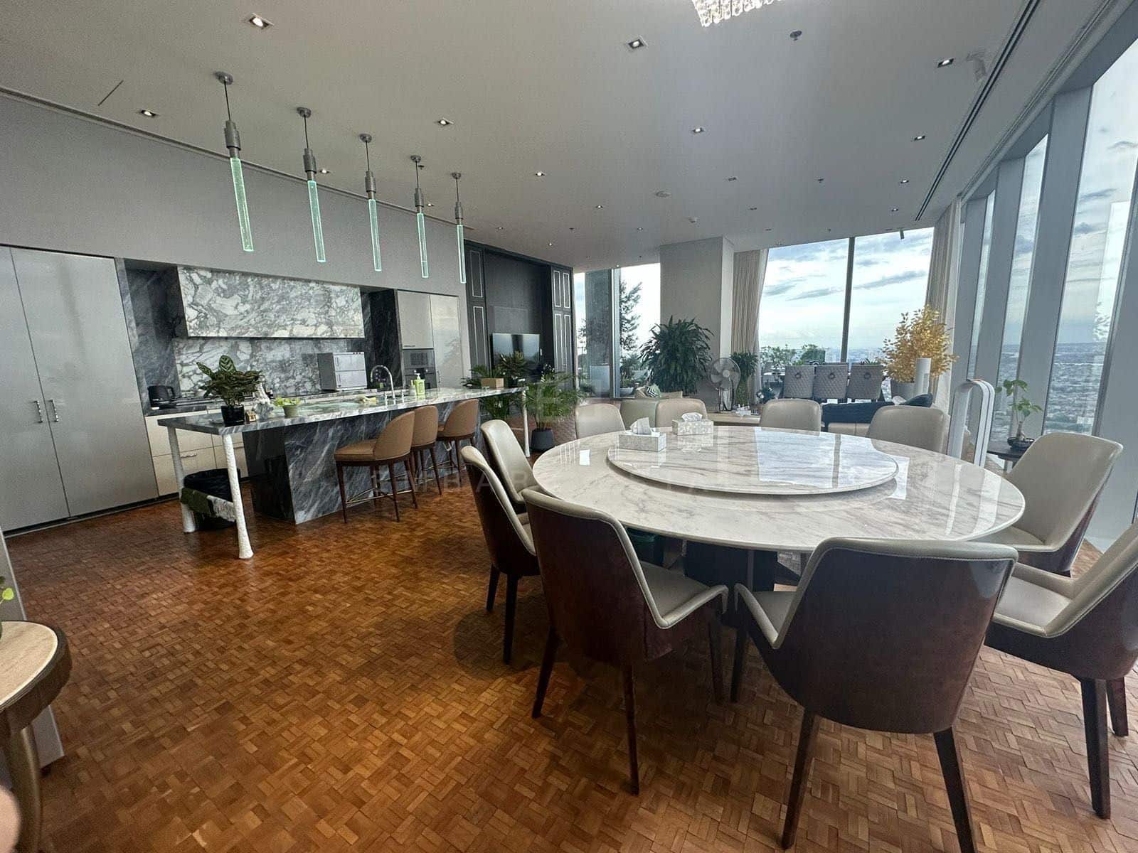 The dining table and kitchen on level 61 at The Ritz-Carlton Residences Bangkok, tube pendants above a dark marble island with breakfast stools